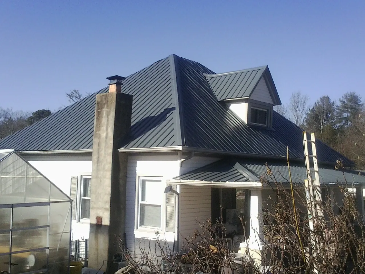 Dark blue standing seam metal roof on a white farmhouse with dormer — Slate & Tile Roof Repair by Roofing Brothers in Meriden